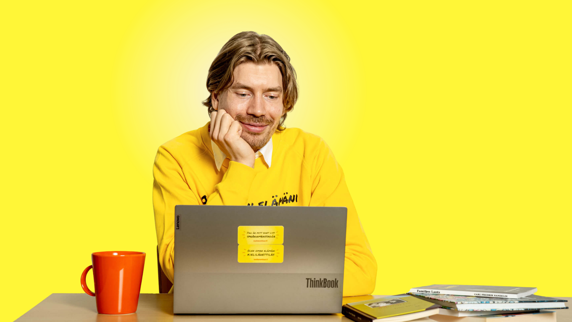 Språkambassadör i gul tröja framför en laptop vid digitalt språkcafé